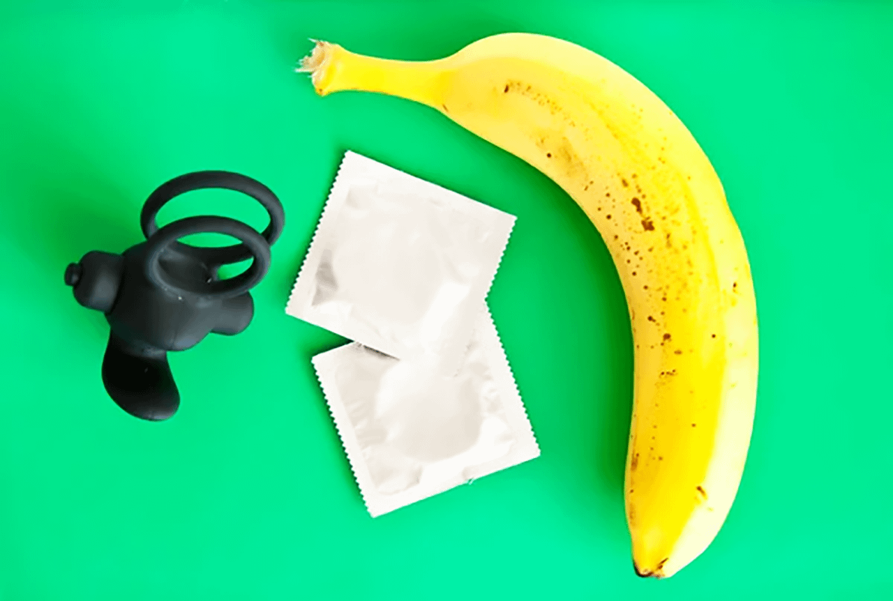Cock ring vibrante nero con banana e preservativi, simbolo di piacere e sicurezza intima, tema trattato da Pommenor.