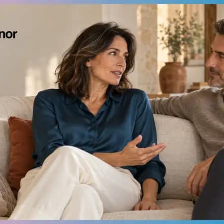 Donna adulta in camicia blu conversa con il partner su un divano chiaro, con logo Pommenor in alto a sinistra.