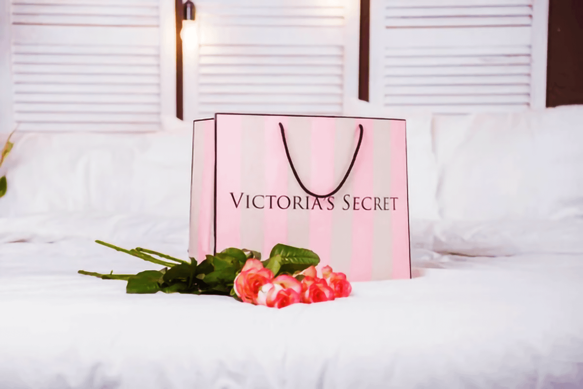 Shopping bag di Victoria's Secret su un letto con rose rosa in vista del Victoria's Secret Show 2024.
