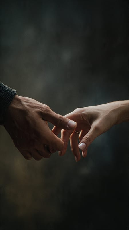 Mani di una coppia che si sfiorano senza toccarsi in un gesto carico di desiderio trattenuto