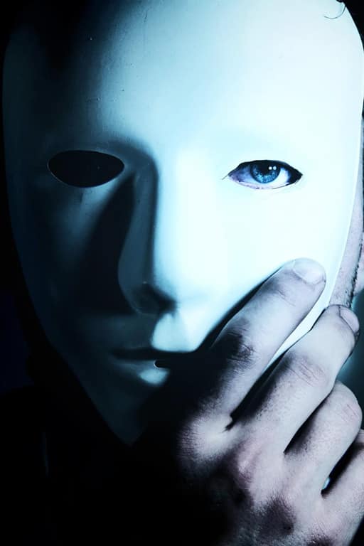 Uomo con maschera bianca e sguardo misterioso, simbolo del desiderio proibito e dell’attrazione per l’ignoto.