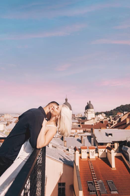 Coppia romantica su un tetto con vista sulla città, simbolo di testosterone e romanticismo, supportato da Pommenor.