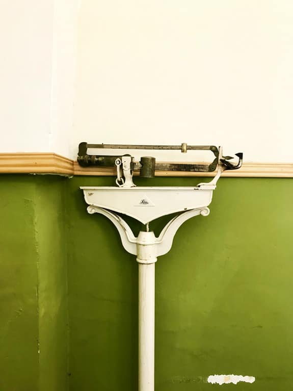 Vecchia bilancia meccanica con sfondo verde, simbolo del monitoraggio del peso e del ruolo della molecola Semaglutide - Pommenor.