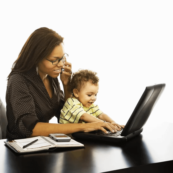 Opportunità di lavoro per mamme italiane: donna che lavora al telefono e al computer con il figlio accanto
