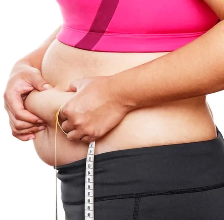 Primo piano di una persona che misura il girovita con un metro, rappresentando l'importanza della cura e della prevenzione dell'obesità.