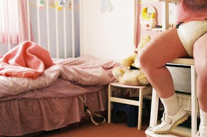 Dettaglio di una stanza con un adulto in pannolino, rappresentazione dell'infantilismo parafilico ABDL.
