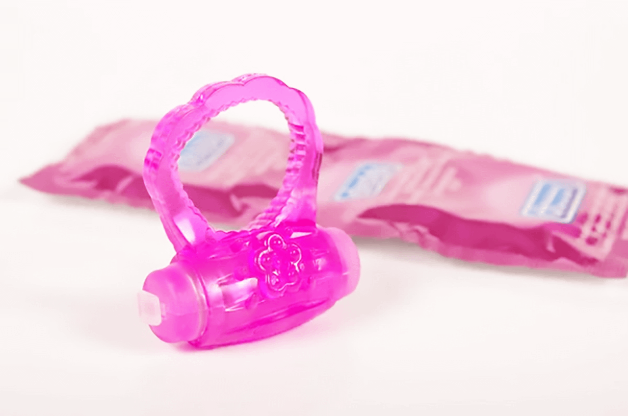 Cock ring vibrante rosa con dettagli floreali e preservativi rosa, al centro del tema benessere su Pommenor.