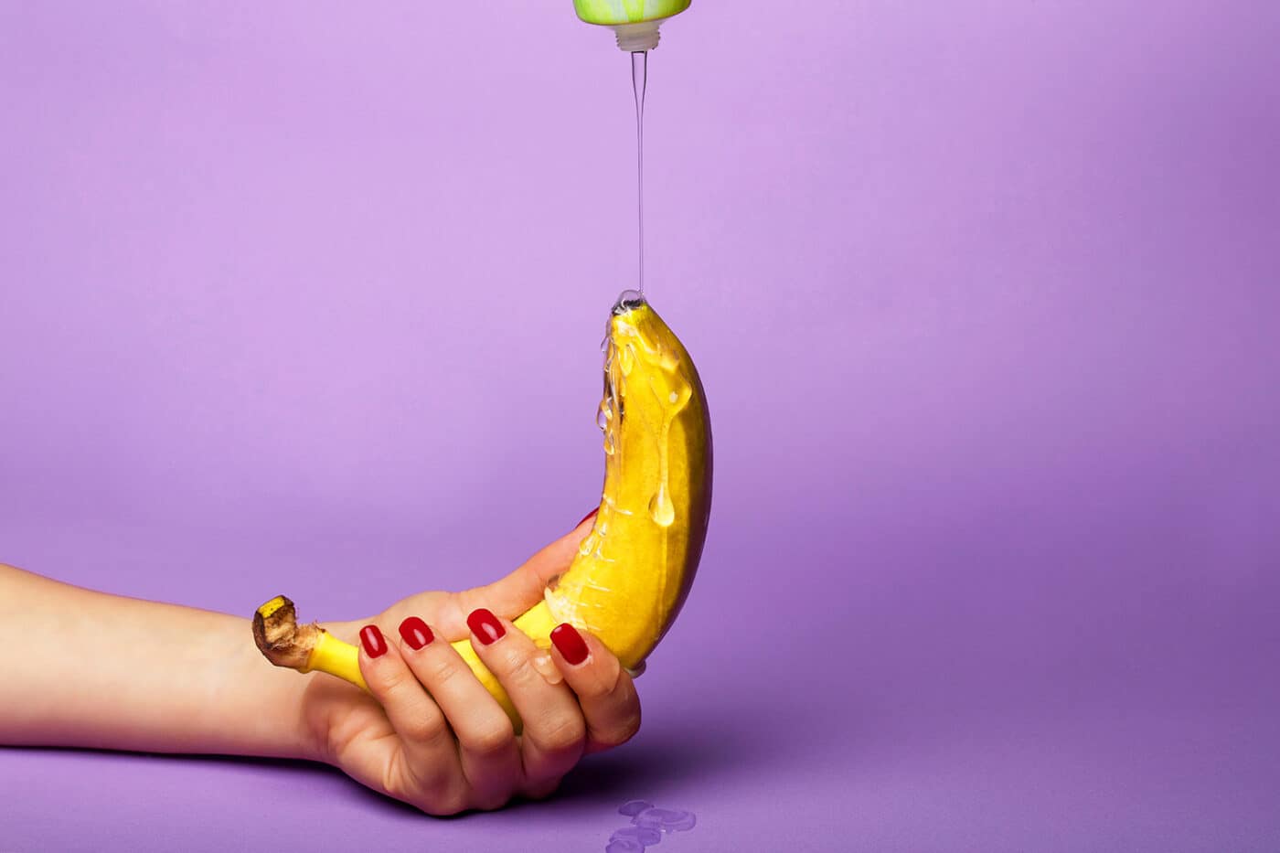 Banana con lubrificante versato, rappresentazione creativa dell’uso di lubrificanti per rapporti intimi.