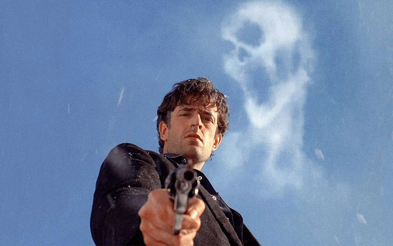 Scena iconica di Dellamorte Dellamore con Rupert Everett che impugna una pistola e uno sfondo inquietante.