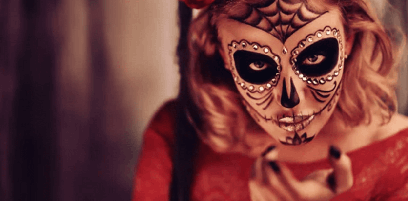 Donna con trucco teschio e fiori rossi per El Día de los Muertos - Pommenor