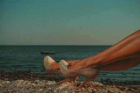 gambe eleganti di escort GFE Pommenor con tacchi beige al tramonto sul mare