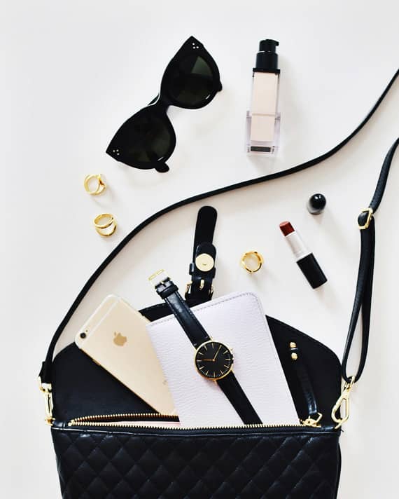Accessori di moda eleganti disposti su una borsa nera che richiamano il tema della seduzione e lusso con Pommenor.