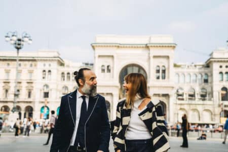 Coppia elegante che passeggia nel centro città, simbolo di complicità e stile della GFE Milano secondo Pommenor.