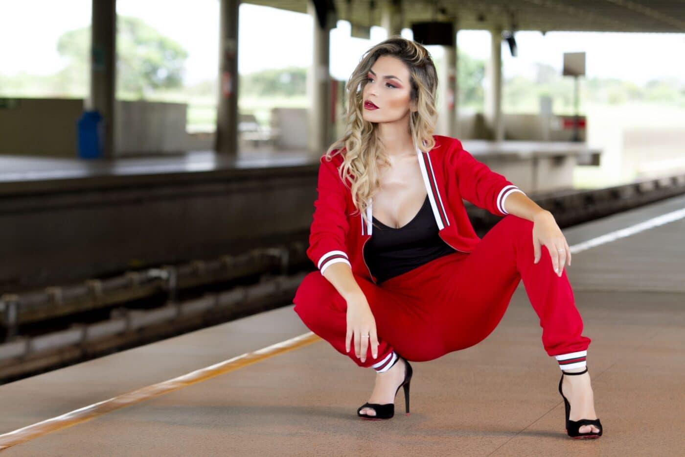 Donna affascinante in tuta rossa e tacchi alti, simbolo dell’unione tra moda e seduzione a Milano nello stile audace di Pommenor.