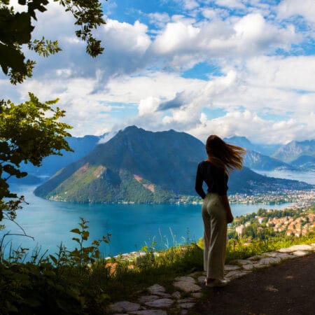Panorama del lago di Lugano con una donna di spalle, immagine ideale per rappresentare l’atmosfera degli incontri con un’escort a Lugano su Pommenor.