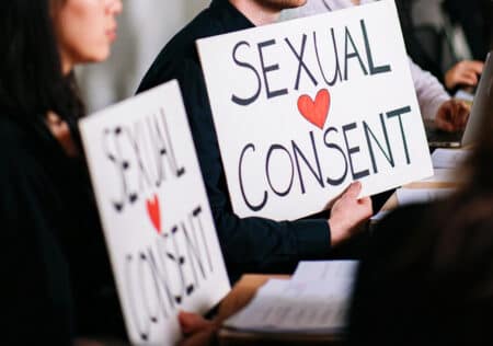 Manifestanti con cartelli dedicati al consenso sessuale durante un incontro pubblico, simbolo di sensibilizzazione e diritto al consenso sessuale.